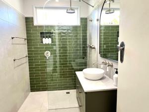 a green tiled bathroom with a sink and a shower at Sausalito- captivating 1950s retro residence in Daylesford +8 photos