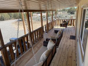 a porch with couches on a porch swing at Zion to Bryce cowboy cabin in Hatch