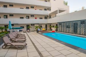 a pool in the courtyard of a building with lounge chairs at Lakeview Apartment Fonyód in Fonyód