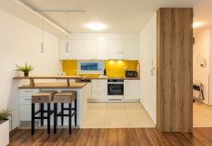 a kitchen with white cabinets and a island with bar stools at Lakeview Apartment Fonyód in Fonyód