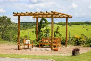 a wooden pergola with two chairs and a bench at Espaço Amplitude in Sobradinho