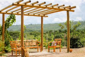 a wooden pergola with two chairs and a bench at Espaço Amplitude in Sobradinho