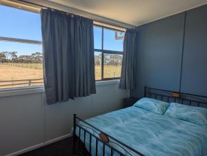 a bedroom with a bed with a view of a field at Cosy Connewarre Cottage in Connewarre