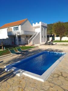 a swimming pool in front of a house at Family friendly house with a swimming pool Dazlina, Sibenik - 23303 in Tisno