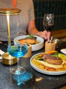 Una mesa con dos platos de comida y una copa de vino. en Best Western Northfields Ealing Hotel, en Londres