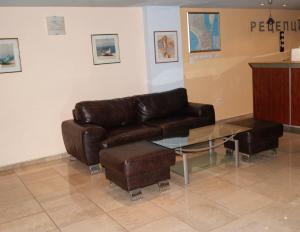 a living room with a leather couch and a glass table at Hotel Fors in Burgas