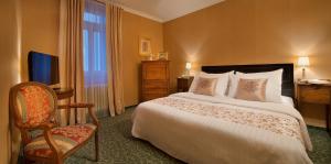 a bedroom with a bed and a chair and a television at Angelis in Prague