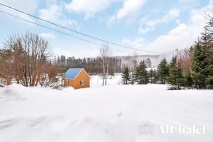 ein kleines Haus auf einem schneebedeckten Feld mit Bäumen in der Unterkunft Lakaban - familial & paisible in Saint-Raymond