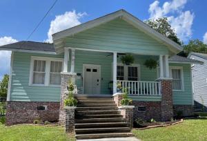 a green house with a porch and stairs at Sparkle City Cottage in Spartanburg