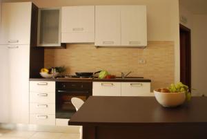 a kitchen with white cabinets and a bowl of fruit on a table at Case Vacanze Anni 20 in Bagheria