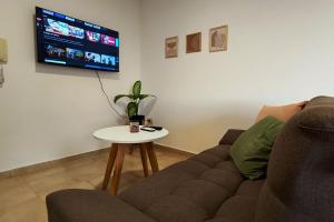ein Wohnzimmer mit einer Couch, einem Tisch und einem Fernseher in der Unterkunft Departamento Moderno - Punto Alto in Villa María