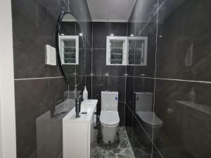 Un baño con lavabo, inodoro y espejo. en Experience Comfort in Our 3-Bedroom Family Home, en Auckland