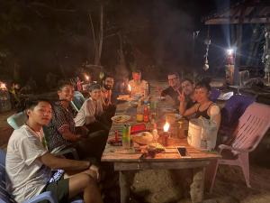 a group of people sitting around a wooden table at Eternal Forest Beach Bar&Bungalow in Koh Chang Ranong
