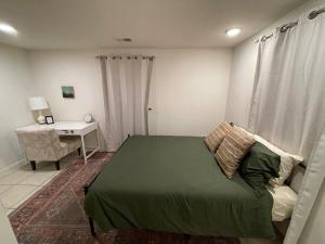 Schlafzimmer mit einem grünen Bett und einem Schreibtisch in der Unterkunft Carolina Cottage in Spartanburg