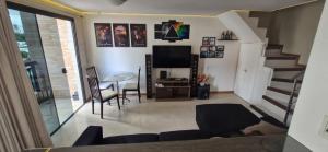 a living room with a staircase and a table and a television at Multiplex Unique DOCA cop30 in Belém