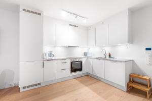 una cucina bianca con mobili bianchi e una sedia di legno di Northern Lights Haven SeaView Ap a Tromsø Altre 12 foto