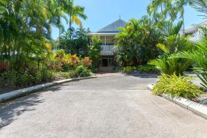 a driveway in front of a house with palm trees at 1 Bedroom ground floor apartment @ Palm Villas in Port Douglas