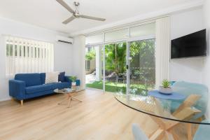 a living room with a blue couch and a glass table at 1 Bedroom ground floor apartment @ Palm Villas in Port Douglas