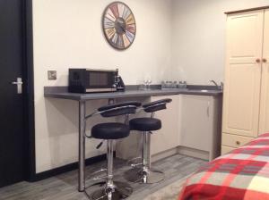 a room with a counter with a microwave and two bar stools at Rooms @ Number Six in Oakham