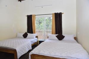 two beds in a room with a window at Ira Homestay By StayApart in Attigundi
