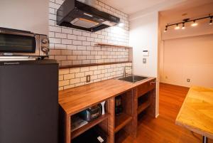 a kitchen with a counter with a sink and a refrigerator at TABiTO Stay Inarimachi in Toyama