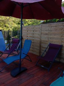 two chairs and an umbrella on a deck at Le Refuge in Saint-Leu