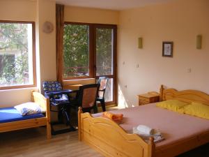 a bedroom with a bed and a desk and two windows at Guest House "Zora - Sarafovo" in Burgas
