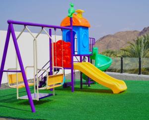 a playground with a slide on the grass at Sheema Lodge in Hatta
