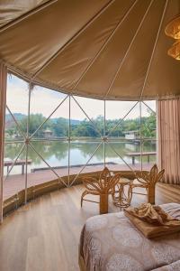 a bedroom with a large window with a view of a river at Eco Eyes Village in Nakhon Nayok