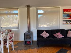 a living room with a black couch and a stove at Hermosa casa en parcela Algarrobo in Algarrobo