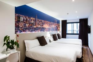two beds in a hotel room with a painting on the wall at Hotel BESTPRICE Gracia in Barcelona