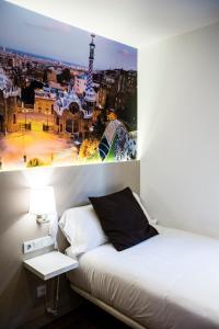 
a room with a bed, a desk and a painting on the wall at Hotel BESTPRICE Gracia in Barcelona
