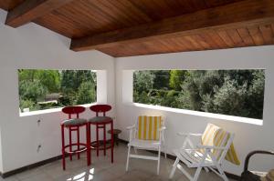 シラクーサにあるVilla Baroneの赤いスツールと椅子、窓のあるポーチ