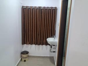 a bathroom with a sink and a shower curtain at Aahvaanam in Kurnool