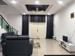 a living room with a couch and a tv and a door at ASSA Homestay in Kuala Terengganu