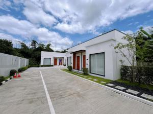 an empty parking lot in front of a white building at มนต์จันทรา เฮ้าส์ in Khlong Lan