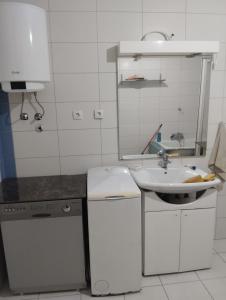 een witte keuken met een wastafel en een spiegel bij Summer house Belgrade in Belgrado