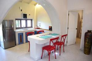 a kitchen with a white counter and red chairs at Casa Recanto - Cosy one bhk house in Sangolda, Goa in Sangolda