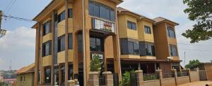 a large yellow building with many windows at Hulcity Hotels Ug in Kyebando
