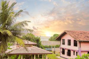 a pink house and a palm tree with the sunset in the background at Sun Rusiru villa in Koggala