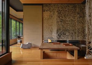 a living room with a wooden table and a wall of glass at Yamanakaonsen Hanamurasaki in Kaga