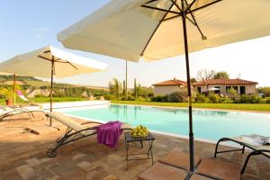 a pool with two chairs and an umbrella and a table with fruit at I Sicomori - Seme di Carota - Glamping e appartamenti con piscina a Saturnia in Saturnia