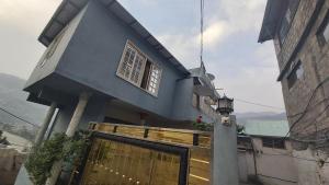 a blue house with a gate and a fence at Kashmir Cottage Muzaffarabad in Muzaffarabad