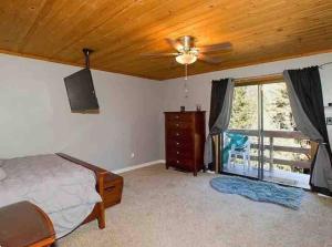 Un dormitorio con una cama y un ventilador de techo. en Sandalwood, en Pine Mountain Club