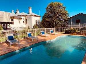 a swimming pool with chairs and a house at The Buchanan 1894 in Parkes