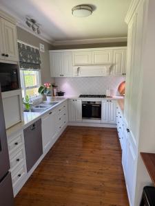 a kitchen with white cabinets and a wooden floor at The Buchanan 1894 in Parkes