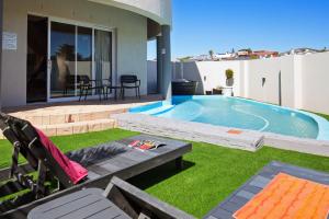 a backyard with a swimming pool and green grass at Luxury Beachfront Villa in Langebaan