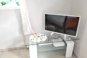 d'une table en verre avec une télévision. dans l'établissement Studio tout confort à Sainte-Anne - 39 m² - Vue sur jardin, à Sainte-Anne