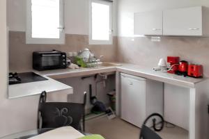 une petite cuisine avec des comptoirs blancs et un micro-ondes dans l'établissement Studio tout confort à Sainte-Anne - 39 m² - Vue sur jardin, à Sainte-Anne