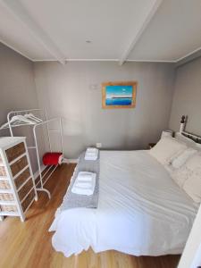 Un dormitorio con una gran cama blanca y una escalera. en Mons Pes in Lakeside, en Ciudad del Cabo
